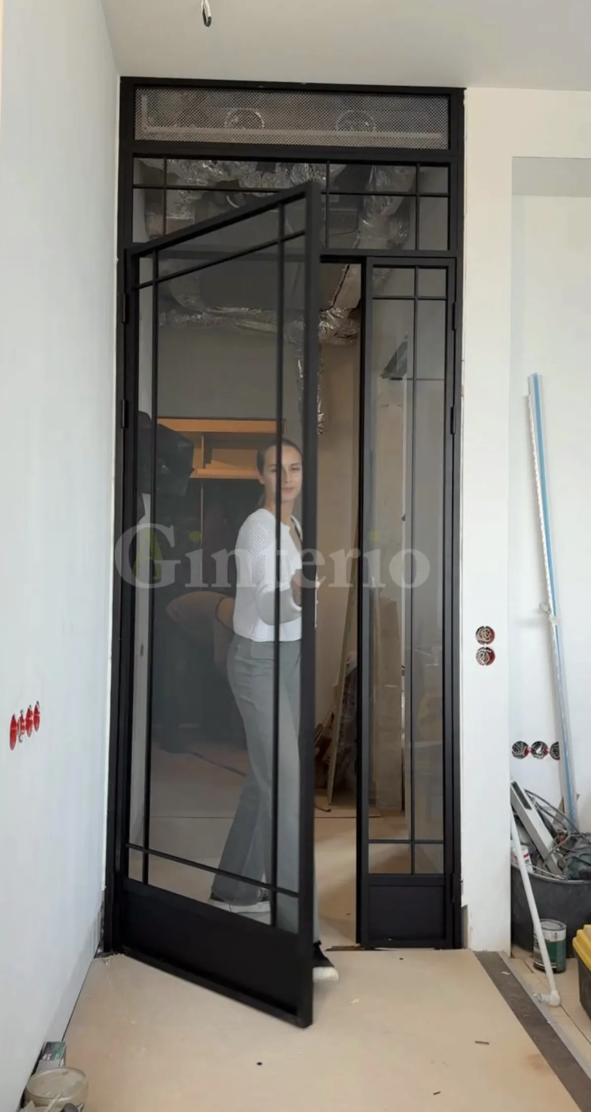 Девушка открывает дверь межкомнатной стеклянной перегородки в стиле лофт от Gintereo, сделанную на заказ в Москве