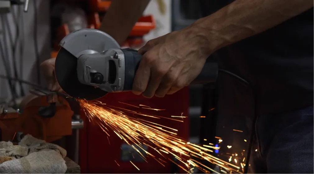 Мастер Gintereo работает с угловой шлифовальной машиной на производстве межкомнатных перегородок из алюминия и стекла